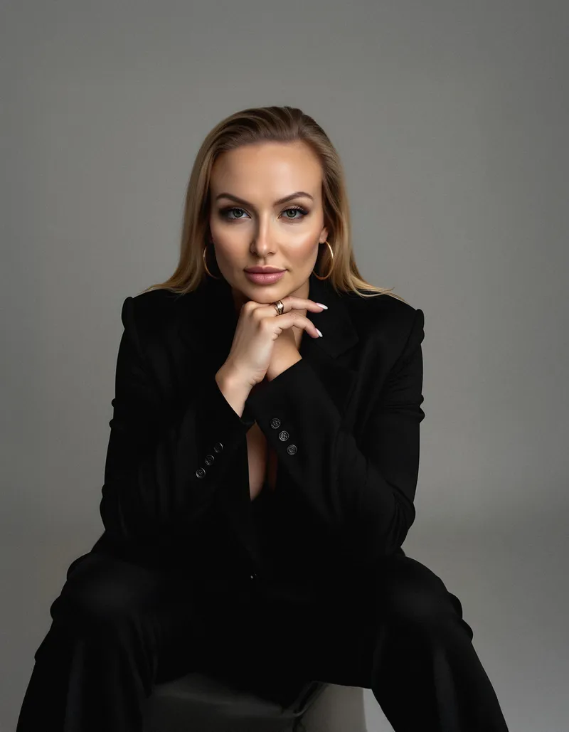 Paulina seated in a black blazer, resting her chin on her hand